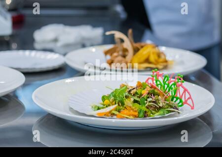 Köstliche frische exotische Salat mit natürlichen Zutaten zum Verkauf auf weißem Teller bei der Küche des Restaurants, Café. Professionelle Küche, Catering, Kochen Stockfoto