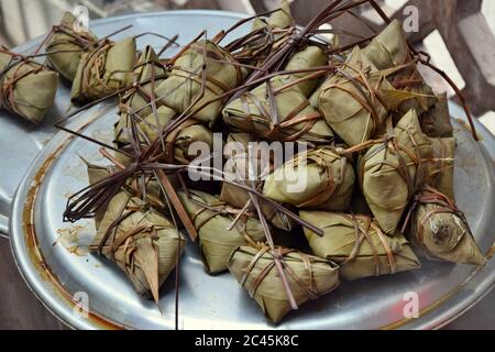 Ein Bündel Reisknödel, Zongzi, zusammengebunden. Zongzi ist ein traditionelles chinesisches Reisgericht aus klejeweidem Reis, der mit verschiedenen Füllungen gefüllt ist. Stockfoto