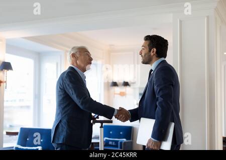 Zwei Geschäftsleute stehen drinnen und schütteln die Hände. Stockfoto