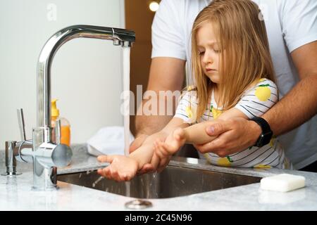 Vater und Tochter waschen sich die Hände über dem Waschbecken in einer Küche Stockfoto