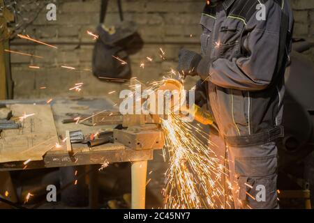 Professionelle schmied Sägen von Metall mit der Kreissäge in der Schmiede, Werkstatt. Handarbeit, Handwerk und Schmiedekunst Konzept Stockfoto