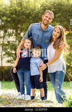 Familienportrait, Mann und Frau stehen draußen mit Jungen und Mädchen, lächelnd an der Kamera. Stockfoto