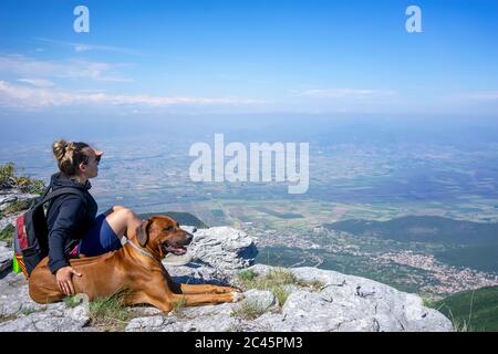 Mädchen mit einem Rhodesian ridgeback Hund in den Bergen. Sommerstimmung. Reisen mit einem Haustier. Liebe Tiere Liebe mein Haustier Stockfoto