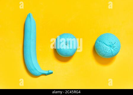 Auf gelbem Hintergrund bemalter Bananenorange Apfel in türkis Farbe Stockfoto