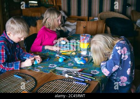 Junge und zwei Mädchen sitzen an einem Tisch in einer Blockhütte, Basteln, Vasterbottens Lan, Schweden. Stockfoto