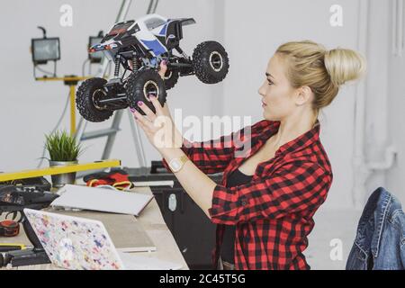 Frau untersucht funkgesteuertes Auto in der Werkstatt Stockfoto