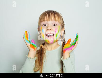 Glücklich überrascht kleines Mädchen mit bunten bemalten Händen Zeichnung. Hübsches Kind Kunst Schüler auf weißem Hintergrund Stockfoto