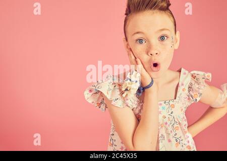 Portrait von Brünette Mädchen tragen Rüschen Kleid mit Blumenmuster auf rosa Hintergrund, Blick auf die Kamera. Stockfoto