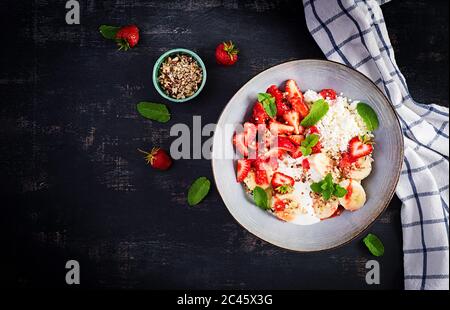 Quark oder Quark mit Erdbeeren, Bananen, Walnüssen in einer blauen Schüssel. Gesunde Ernährung. Draufsicht, Overhead, Kopierbereich Stockfoto