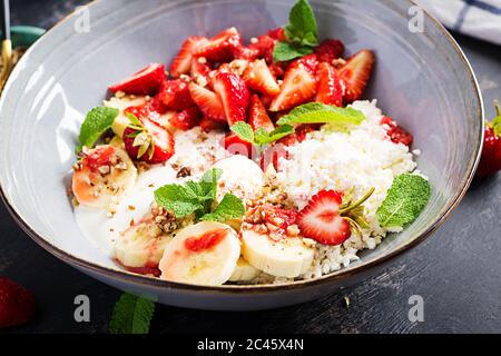 Quark oder Quark mit Erdbeeren, Bananen, Walnüssen in einer blauen Schüssel. Gesunde Ernährung. Stockfoto