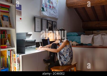 Mädchen sitzt in ihrem Schlafzimmer, Hausaufgaben während Coronavirus Lockdown. Stockfoto