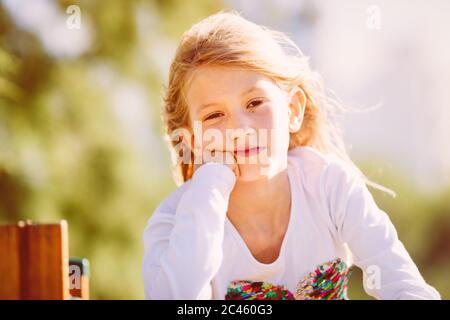 Porträt eines niedlichen Mädchen, Grundschulalter, mit blonden Haaren fliegen im Wind Stockfoto