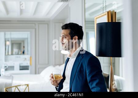 Geschäftsmann mit iced Drink, tief in Gedanken versunken in der Suite Stockfoto