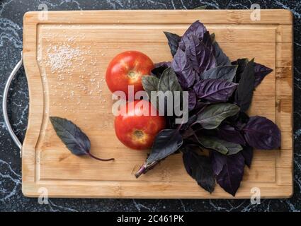 Zwei rote Tomaten und lila Basilikumblätter Stockfoto