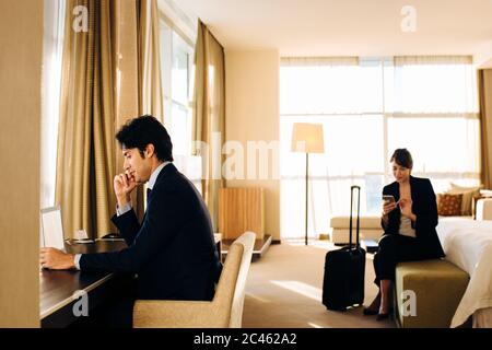 Kaufmann und Kauffrau im Hotel Schlafzimmer arbeiten Stockfoto