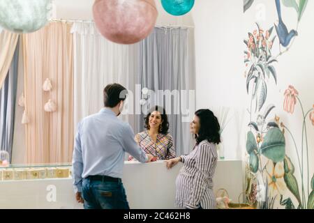 Ladenbesitzer und schwangere Paare an der Kasse Stockfoto