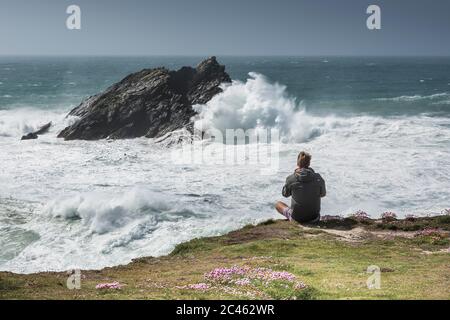 Ein Tourist, der die dramatische Aussicht von Pentire Point East an der Küste von Newquay in Cornwall genießt. Stockfoto