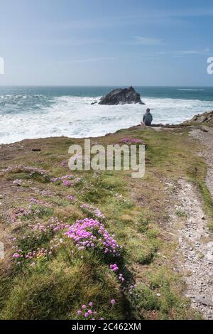 Ein Tourist, der die dramatische Aussicht von Pentire Point East an der Küste von Newquay in Cornwall genießt. Stockfoto