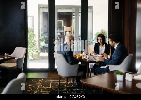 Zwei Geschäftsleute und Frau mit Mittagessen im Hotel Restaurant Stockfoto