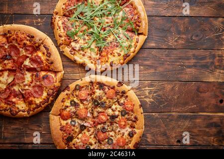 Zusammensetzung von drei verschiedenen Arten Pizza auf hölzernen Tisch Stockfoto