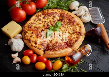 Köstliche italienische Pizza auf schwarzen Holztisch serviert. Stockfoto