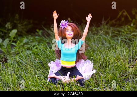 Tambow, Russische Föderation - 12. Juni 2020 Brünette Barbie-Puppe tun Yoga in der Lotus-Haltung im Freien Stockfoto