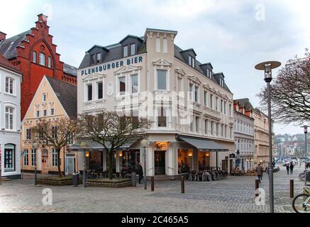 FLENSBURG, DEUTSCHLAND. JANUAR 28, 2020. Schmale Gasse einer kleinen Stadt mit alten Häusern und Menschen, die herumlaufen. Gebäude mit deutscher Architektur Stockfoto