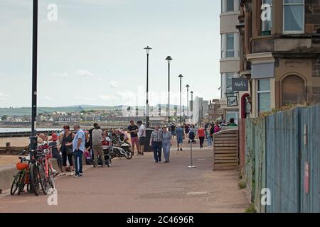 Portobello, Edinburgh, Schottland, Großbritannien. 24. Juni 2020. Das heiße Wetter brachte Familien raus, aber am Meer war nicht viel los, am Strand und an der Promenade gab es viel Platz, um sich in sozialer Distanz zu halten. Leute auf verschiedenen Paddelbrettern und Schlauchboote und andere mit Picknicks am Sandstrand. Stockfoto