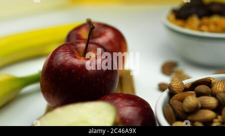 Ein Apfel, ein Maßband, Nüsse und auf einem weißen Hintergrund platziert erinnern Sie an richtige Ernährung und eine schöne Figur. Stockfoto