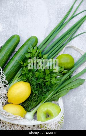 Umweltfreundlicher, wiederverwendbarer Netzbeutel mit frischem Gemüse und Obst auf Steintisch. Draufsicht. Konzept für die Lieferung von Lebensmitteln Stockfoto