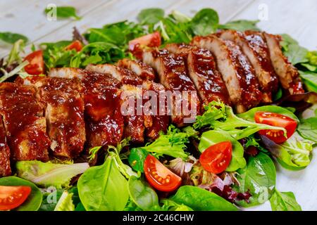 Gebackene Spare Baby Rücken Rippchen mit grünem Salat und Tomaten. Stockfoto