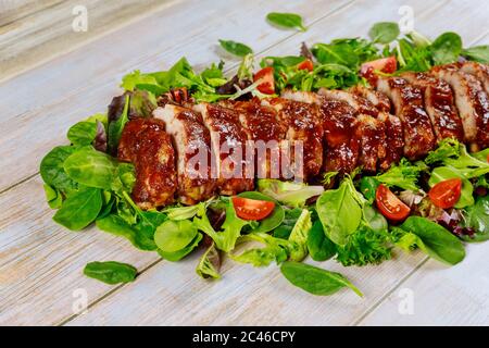 BBQ Schweinefilet oder Filet auf grünen Blättern mit Tomaten. Stockfoto