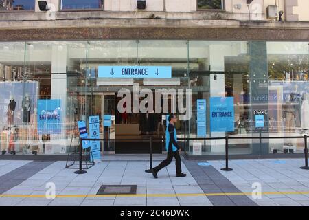 Ein Foto des Cardiff Next Store mit sozialen Distanzmarkierungen, Tensa Barrieren und Beschilderung. Keine Schlange, ein Mann ging vorbei. Stockfoto