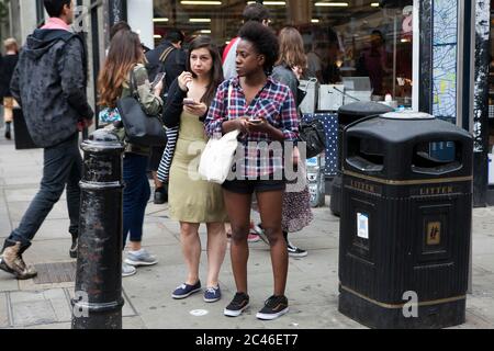 London, Großbritannien - am 17. Juli 2019 überlegen zwei Mädchen mit Telefonen, wohin sie als nächstes gehen sollen. Stockfoto