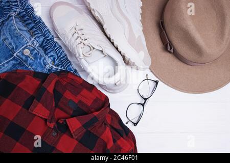 Flache Lay-Komposition mit rotem Hemd, Hut und Sneakers. Stockfoto