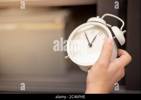 Weibliche Hand hält die klassische weiße Uhr für zeigen den Zeitpunkt des Lebens und der Zeit ist wichtig Konzept. Stockfoto