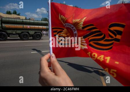 Moskau, Russland. 24. Juni 2020 EINE Frau winkt rote Fahnen trifft Militärfahrzeuge aus der Victory Day Militärparade auf dem Roten Platz anlässlich des 75. Jahrestages des Sieges im Zweiten Weltkrieg Paraden des Siegestages in ganz Russland wurden vom 9. Mai auf den 24. Juni verschoben, da Beschränkungen auferlegt wurden, um die Ausbreitung des neuartigen Coronavirus zu verhindern Stockfoto