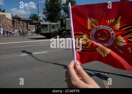 Moskau, Russland. 24. Juni 2020 EINE Frau winkt rote Fahnen trifft Militärfahrzeuge aus der Victory Day Militärparade auf dem Roten Platz anlässlich des 75. Jahrestages des Sieges im Zweiten Weltkrieg Paraden des Siegestages in ganz Russland wurden vom 9. Mai auf den 24. Juni verschoben, da Beschränkungen auferlegt wurden, um die Ausbreitung des neuartigen Coronavirus zu verhindern Stockfoto
