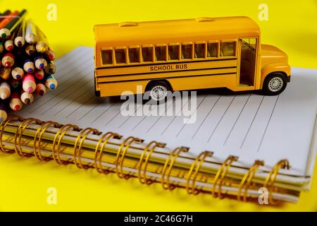 Zurück zur Schule cocept Hintergrund. Gelber Spielzeugbus mit Notizblock und Farbstiften. Stockfoto