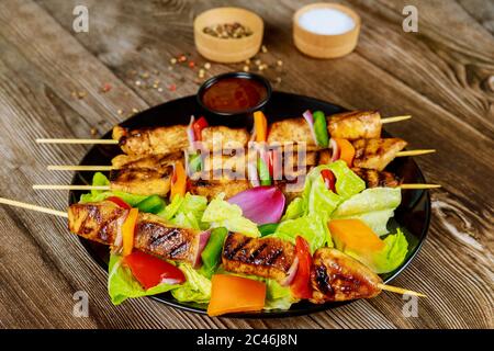Hähnchenkebab auf Holzspieß mit Salat und heißer Sauce. Stockfoto