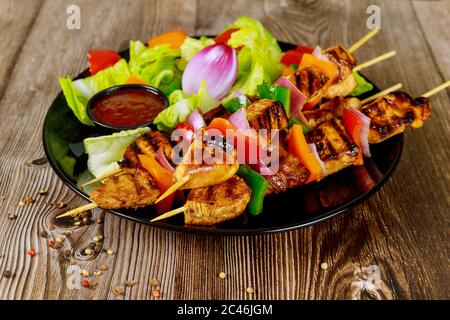 Hausgemachter Schischkebab auf Spieß mit Gemüse auf Holzhintergrund. Stockfoto