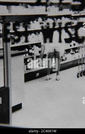 Feine 70er Jahre vintage Kontaktdruck schwarz-weiß Fotografie einer Frau Einkaufen in einem Lebensmittelgeschäft. Stockfoto