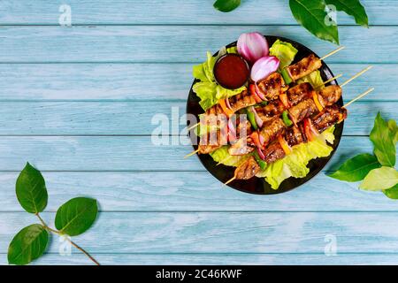 Lammkotelchen auf Spieß mit Gemüse auf Holzhintergrund. Draufsicht. Stockfoto