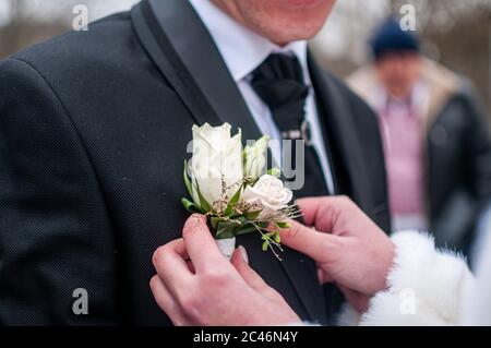 Braut trägt Bonbonniere auf der Bräutigam Jacke Stockfoto