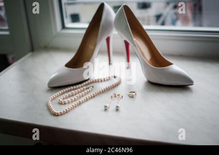 Hochzeitsaccessoires mit weißen Schuhen auf dem Tisch neben dem Fenster Stockfoto