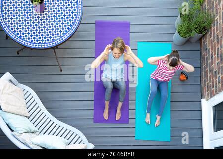 Overhead-Ansicht Von Mutter Und Tochter, Die Gemeinsam Zu Hause Auf Deck Trainieren Stockfoto