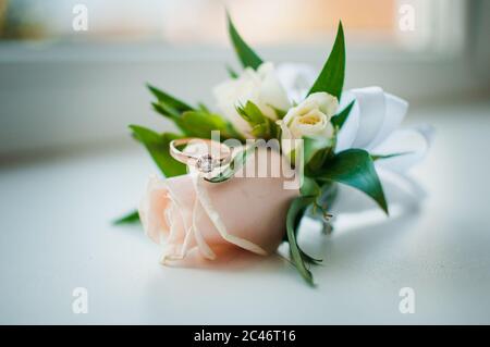 Weiß und rosa boutonniere und Gold Ring mit Edelstein auf dem weißen Hintergrund Stockfoto