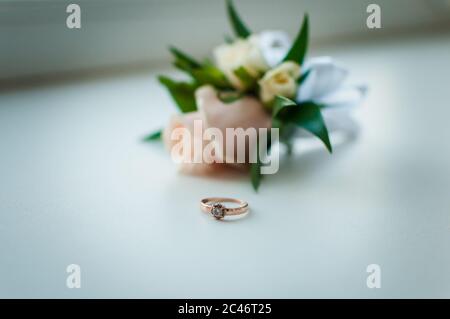 Weiß und rosa boutonniere und Gold Ring mit Edelstein auf dem weißen Hintergrund Stockfoto