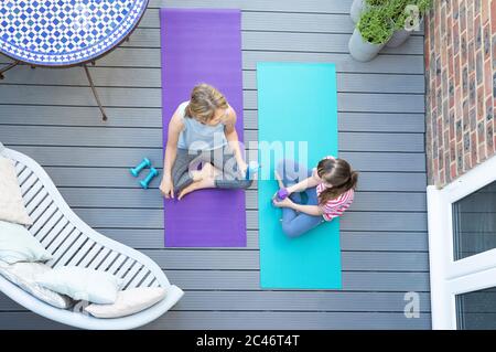 Overhead-Ansicht Von Mutter Und Tochter, Die Sich Ausruhen Und Unterhalten, Nachdem Sie Zusammen Zu Hause Auf Deck Trainiert Haben Stockfoto