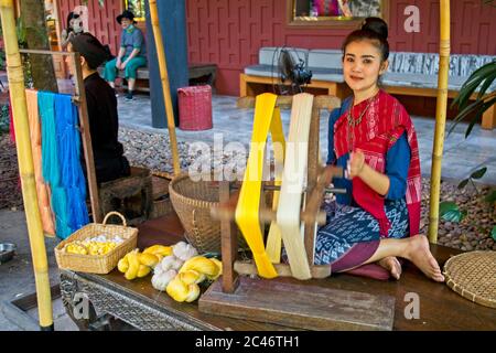 Thailändische Seidenhandwerk lokale Frau in traditionellen Kleid Vorführung Spinning Seidenfaden Webstühle von verschiedenen farbigen Faden zu sehen Stockfoto